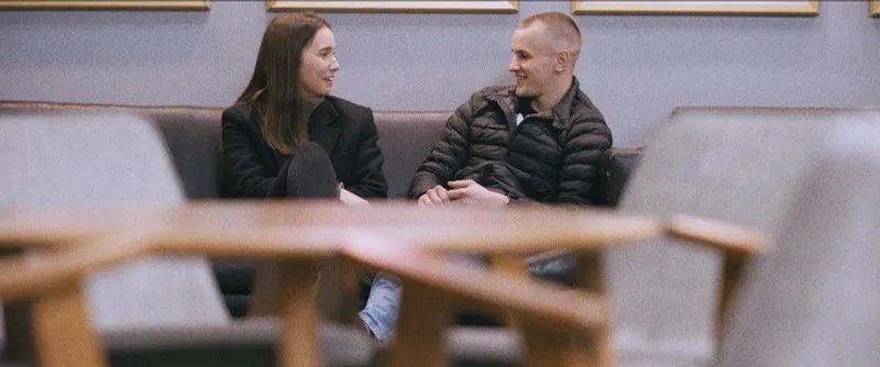 Olimpia Konczalska and Łukasz smile at each other on a sofa