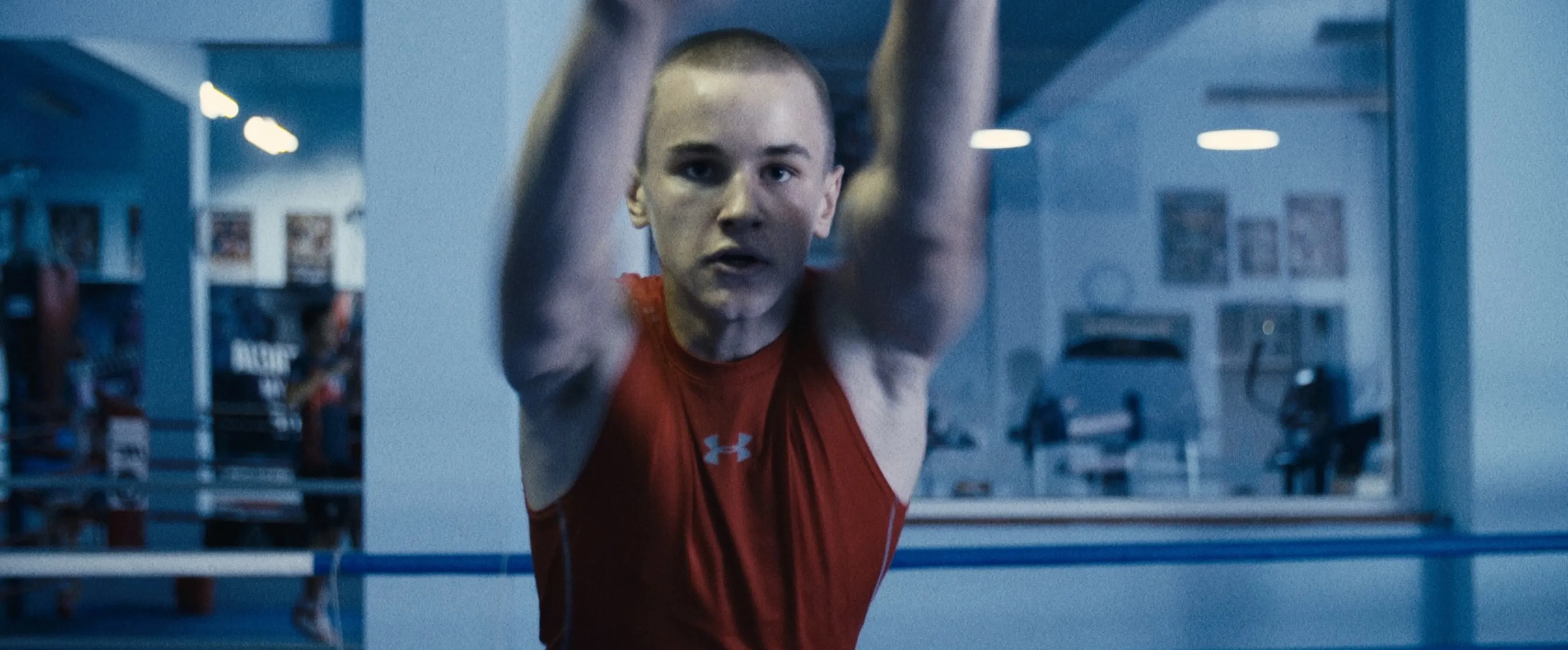 Łukasz Perkowski in a red training vest, mid-exercise in a boxing gym